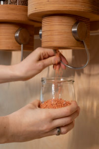 Woman fills lentils into a glass, detail from an unwrapped shop. Woman fills lentils into a glass, detail from an unwrapped shop.
